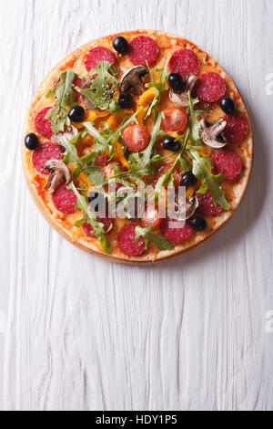 Heiße italienische Pizza mit Rucola und Salami, vertikale Ansicht von oben Stockfoto