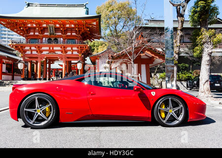 Roten Ferrari 458 Italia in der Nähe von Vermillion zwei geparkte - Geschichte Romon Tor der beliebten Ikuta Shinto Schrein n Kobe, Japan. Strahlender Sonnenschein, blauer Himmel. Stockfoto