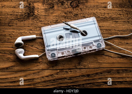 Retro-kompakten Kassette mit Brötchen und weiße Mikro Kopfhörer auf Holztisch Textur. Audio-Hintergrund