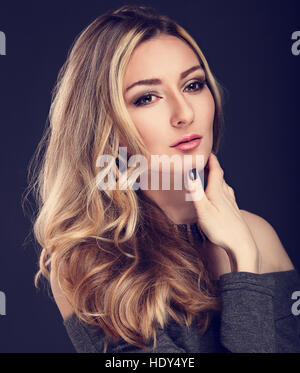 Denken-Business-Dame mit langen blonden Haaren und nachdenklichen Blick auf grauem Hintergrund. Getönten Closeup portrait Stockfoto
