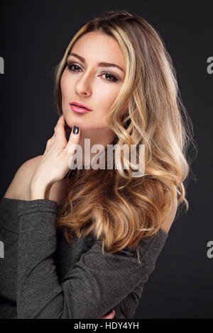 Denken-Business-Dame mit langen blonden Haaren und nachdenklichen Blick auf grauem Hintergrund Stockfoto