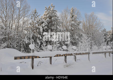 die Überreste des Zauns auf einem verlassenen Ort mit Schnee Kappen auf Pole Stockfoto