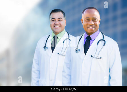 Gut aussehend Afroamerikaner und hispanischen männlichen Ärzten außerhalb der Gebäude des Krankenhauses. Stockfoto