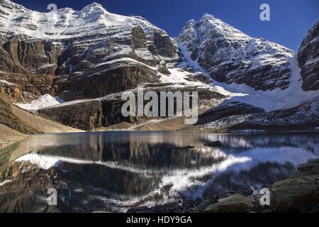 Verschneite Berggipfel spiegeln sich in noch Wasser des Lake Oesa im Yoho National Park, Lake O'Hara Region, Kanadischen Rocky Mountains Stockfoto