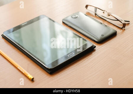 auf Tisch legen, Gläser und eine Tablette, ein Smart-Phone und einen Bleistift Stockfoto