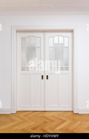 Weiße alte doppelte Schiebetür mit strukturiertem Glas in einem historischen Gebäude mit Eiche Parkett Böden, Kopie oder Text Platz Stockfoto