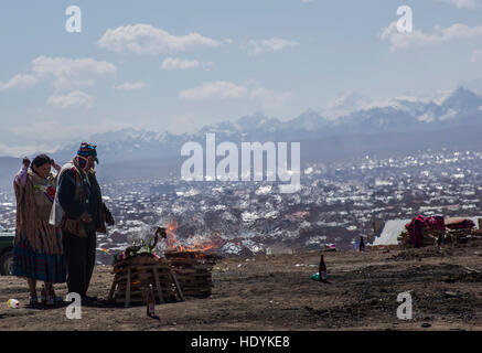 Eine bolivianische paar Anzeigen eine Mesa, das Angebot auf der Pachamama oder Mutter Erde Gott in Bolivien mit Bergen im Hintergrund Stockfoto