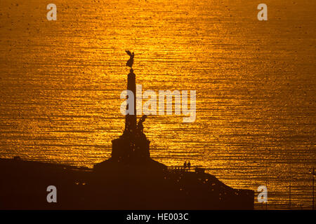 Aberystwyth Wales UK, Donnerstag, 15. Dezember 2016 UK Wetter: die Sonne untergeht in einem Flammenmeer aus goldenem Licht über die Cardigan Bay, mit dem ikonischen Aberystwyth War Memorial in der Silhouette Foto © Keith Morris / Alamy Live News Stockfoto