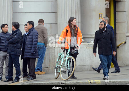 London, UK, 16.12.2016, schiebt eine Frau ihr Fahrrad über die Kreuzung als Fahrt durch es.  Die City of London Corporation hat angekündigt, dass Autos, Taxis und LKWs an Wochentagen von 07:00 bis 19:00 von der belebten Kreuzung für einen 18-Monats-Testversion verboten werden. Nur Busse, Radfahrer und Fußgänger dürfen. Vorausgegangen war den Tod eines Radfahrers Ying Tao. Stockfoto