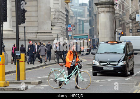 London, UK, 16.12.2016, schiebt eine Frau ihr Fahrrad über die Kreuzung als Fahrt durch es.  Die City of London Corporation hat angekündigt, dass Autos, Taxis und LKWs an Wochentagen von 07:00 bis 19:00 von der belebten Kreuzung für einen 18-Monats-Testversion verboten werden. Nur Busse, Radfahrer und Fußgänger dürfen. Vorausgegangen war den Tod eines Radfahrers Ying Tao. Stockfoto