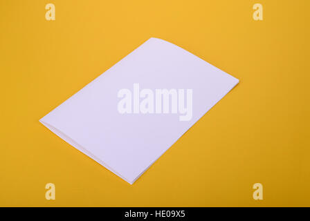 White-Paper Bifold Broschüre Mockup auf gelbem Hintergrund Stockfoto