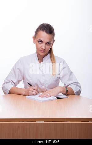 Die schöne Frau in einem medizinischen Anzug mit Stift in der Hand und notebook Stockfoto