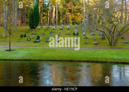 Bredakra, Schweden - 14. Dezember 2016: Dokumentation der Ortsfriedhof. Teich ist nach einer kalten Nacht gefroren. Grabsteine am gegenüberliegenden Hang. Stockfoto