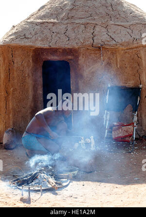 NAMIBIA, KAMANJAB, Oktober 10: Himba-Mann passt im Kamin Holz Souvenirs für Touristen, die in das Dorf der Himba Leute in der Nähe von Kamanjab in Nord- Stockfoto