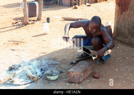 NAMIBIA, KAMANJAB, Oktober 10: Himba-Mann passt im Kamin Holz Souvenirs für Touristen, die in das Dorf der Himba Leute in der Nähe von Kamanjab in Nord- Stockfoto