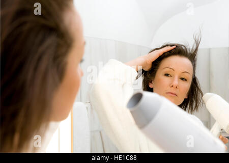 Junge Frau Föhnen ihre Haare im Bad Stockfoto