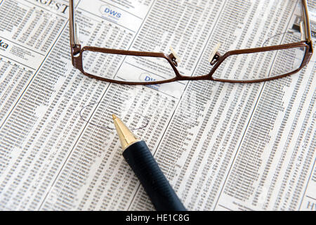 Gläser und Stift liegen auf den Finanzteil einer Tageszeitung Stockfoto