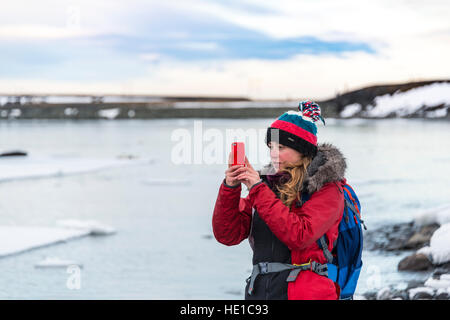 Junge Frau nehmen Foto mit Handy, Fjallsárlón Gletscherlagune, Island Stockfoto
