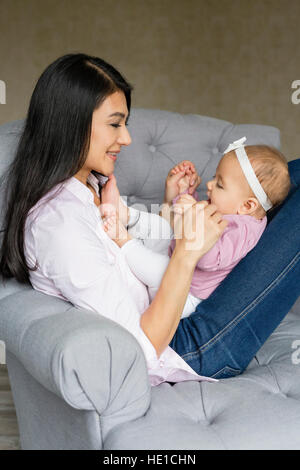 Mutter sitzt mit Baby auf einem Sessel Stockfoto