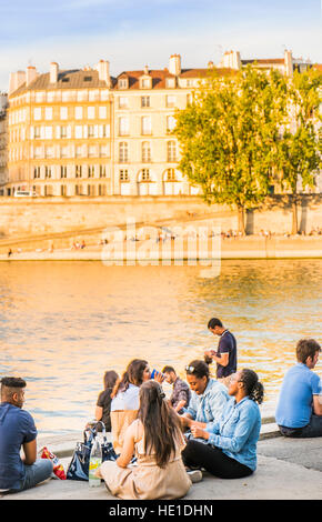 junge Menschen mit einem Picknick am Ufer des Fluss Seine in der Abenddämmerung Stockfoto