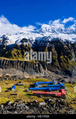 Luftaufnahme auf die Häuser der Annapurna Base Camp, Gletscher und Schnee bedeckt Annapurna-Gebirge in der Ferne Stockfoto