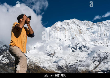 Ein Fotograf ist eine Aufnahme von der kargen Landschaft der Annapurna Base Camp, die schneebedeckte Annapurna 1 North Face in der Ferne Stockfoto
