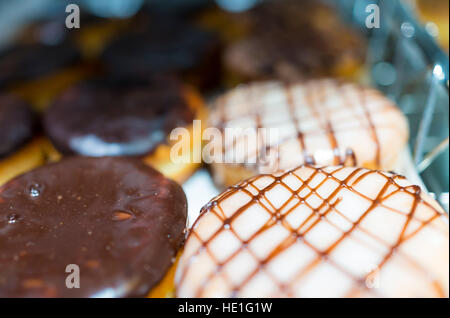 Anzeige von Schokolade und Karamell glasierte Donuts in einer Bäckerei Stockfoto