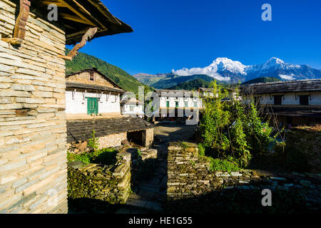 Blick auf einige Häuser des historischen Dorfes mit der Berge Annapurna Süd (links), himchuli (rechts) in der Ferne Stockfoto