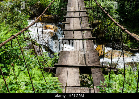 Eine alte, hölzerne Hängebrücke ist einen kleinen Fluss im oberen Modi Khola Tal überqueren. Stockfoto