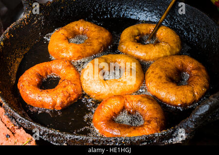 Donuts sind in einer Pfanne mit heißem Öl gebraten. Stockfoto