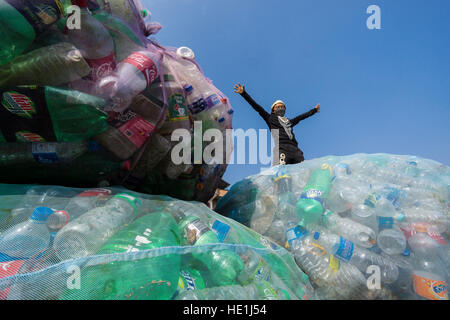 Ein Arbeiter steht auf große Netze voll von leeren Plastikflaschen, gesammelt in der Stadt für das recycling Stockfoto