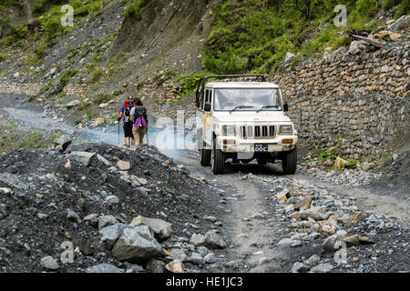 Zwei Touristen sind zu Fuß entlang der Straße im oberen marsyangdi Tal, ein Jeep ist die Herstellung von exhaus Gase Stockfoto