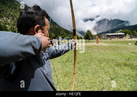 Ein lokaler Mann übt Bogenschießen auf einem Dorffest im oberen marsyangdi Tal Stockfoto