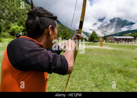 Ein lokaler Mann übt Bogenschießen auf einem Dorffest im oberen marsyangdi Tal Stockfoto