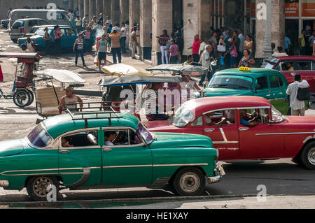 Havanna, Kuba - ca. Juni 2011: Bunte Vintage American Taxi Autos die Straße teilen mit Fahrradrikscha auf einer belebten Straße im Centro. Stockfoto