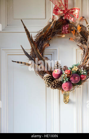 Weihnachten-Feder, Obst Laub Kranz auf Holztür. Cotswolds, Gloucestershire, England Stockfoto