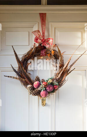 Weihnachten-Feder, Obst Laub Kranz auf Holztür. Cotswolds, Gloucestershire, England Stockfoto