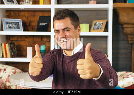 Junger Mann lächelnd und zwei Daumen nach oben zeigen Stockfoto