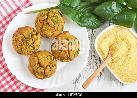 Vegane Muffins mit Spinat und Maismehl serviert auf weißen Teller auf weißem rustikalen Hintergrund. Ansicht von oben Stockfoto