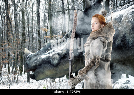 Wildes Mädchen Bogenschütze in einem Wald mit Bogen und triceratops Stockfoto