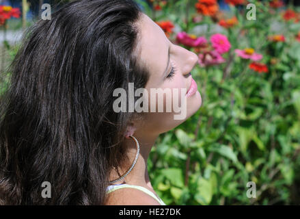 Porträt der jungen attraktiven Frau unter den Sommerblumen Stockfoto