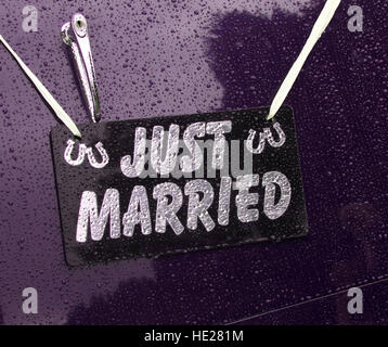 Just Married Schild hängen auf der Rückseite des lila Oldtimer Hochzeitsauto im Regen. Stockfoto