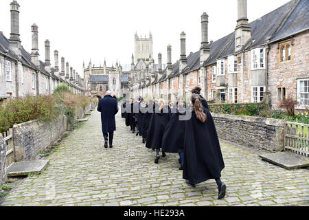 Chorsänger aus Wells Cathedral Choir entlang enger Vikare mit Wells Cathedral im Hintergrund, am Ostersonntag. Stockfoto