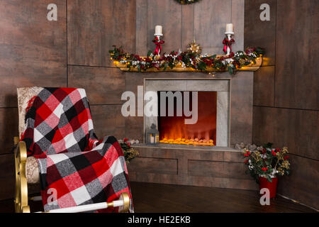 Schaukelstuhl mit einer Decke im Wohnzimmer mit eingerichteten modernen flammenden Kamin Stockfoto