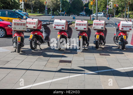 Eine Reihe von Telepizza Motoscooters geparkt auf einem Bürgersteig in Barcelona, Spanien mit ihrer Lieferung-Boxen auf dem Rücken befestigt. Stockfoto