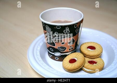 Pappbecher Kaffee und Sandwich Cookies mit Erdbeermarmelade in Kunststoffplatte auf Holztisch Stockfoto