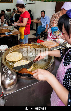 Hui uigurischen Frau Vorbereitung Braten Nang Fladenbrot muslimischen Viertel Lebensmittelmarkt Xian, China. Stockfoto