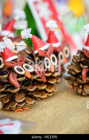 Weihnachts-Dekoration mit Tannenzapfen. Vögel aus Tannenzapfen mit Santa Hüte hergestellt. Stockfoto