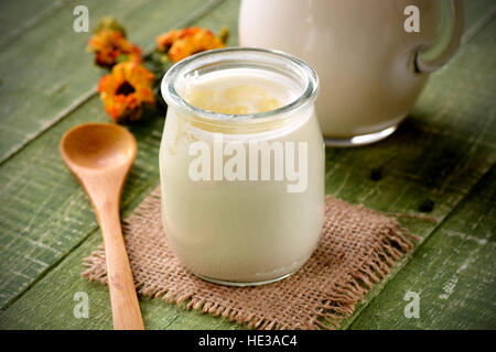 weiße Joghurt im Glas am grünen Tisch zum Frühstück Stockfoto