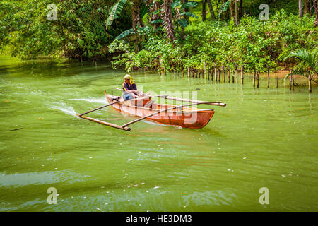 Ein Filipino Mann Paddel seine Ausleger-Ponton-Boot entlang der Loboc River auf Bohol Island, Philippinen, Südostasien. Stockfoto